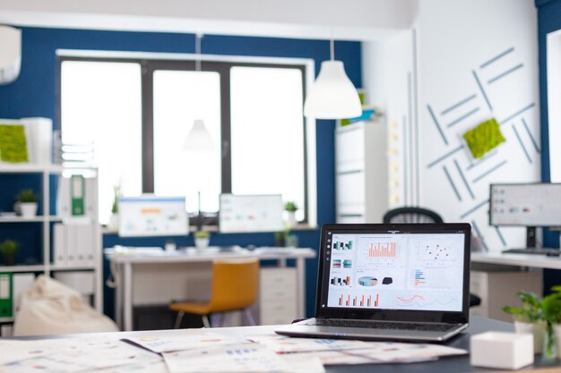 Interior de la acogedora sala de empresa luminosa con laptop, lista para la lluvia de ideas, sillas modernas y elegantes, todo listo para los empleados. Oficina espaciosa vacía de espacio de trabajo creativo.