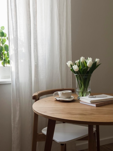 Interior aconchegante um buquê de tulipas em um vaso uma chávena de livros de chá em uma mesa redonda de madeira