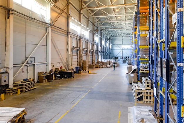 Foto interior de un almacén moderno con filas y cajas de mercancías en estanterías altas