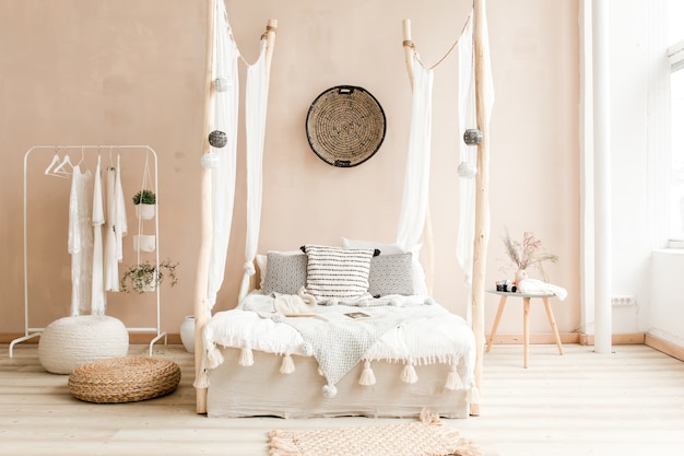 Interior del amplio dormitorio de estilo escandinavo con cama gris y planta de ficus en una maceta