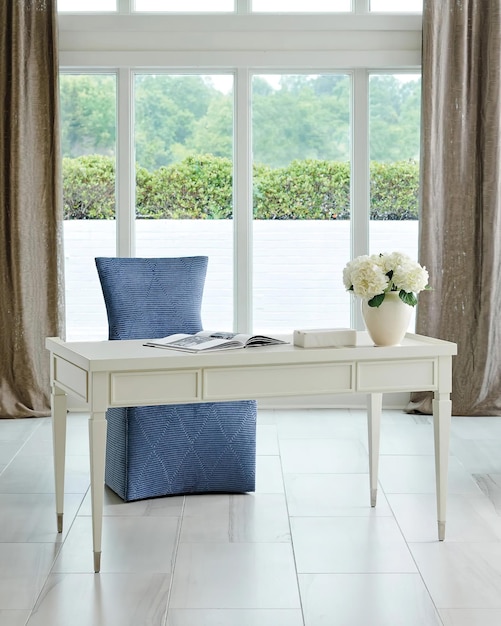 Interior de apartamento de lujo con mesa blanca, gran sillón azul y grandes ventanas