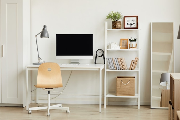 Interior de apartamento minimalista con enfoque en el escritorio de la computadora contra la pared blanca