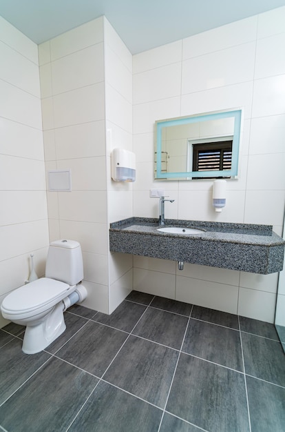 Interior de baño comercial con lavabos de granito Baño moderno equipado en clínica Espejo en pared de azulejos Primer plano
