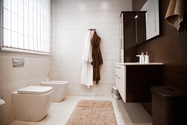 Interior de baño nuevo y luminoso con cabina de ducha de vidrio que rodea el gabinete de tocador marrón y combinado con azulejos de mosaico