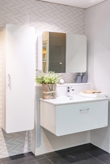 Interior de baño con pared blanca, muebles vintage, toallas, inodoro y lavabo.