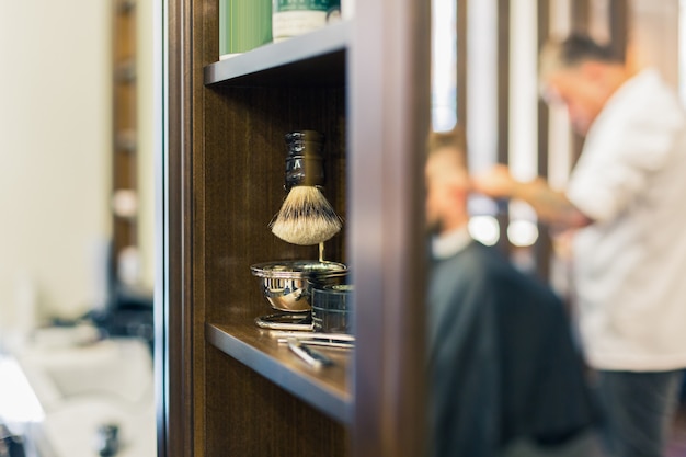 Interior de barbería de lujo, muebles caros azules, adornos de madera, techo negro de moda, batas blancas en los respaldos de los sillones