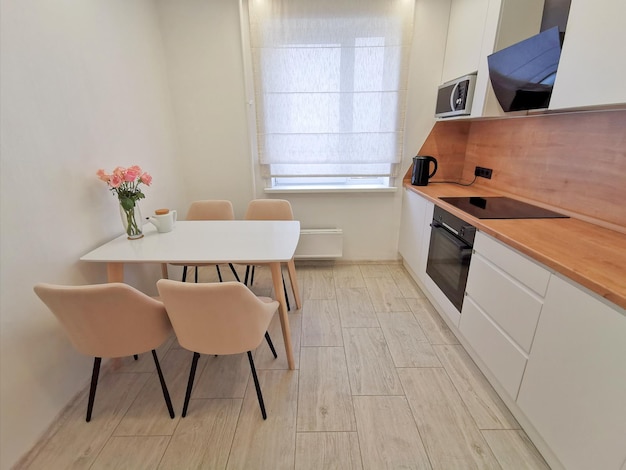 Interior branco pequeno da cozinha. Apartamento minimalista moderno em branco com elementos em preto e madeira