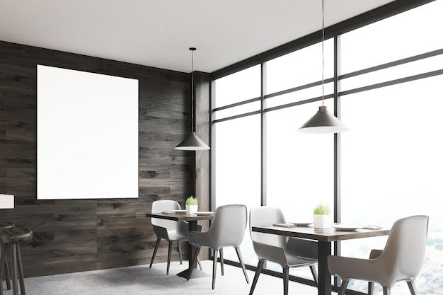 Interior de café de madera oscura con mesas cuadradas, sillas blancas a lo largo de una ventana panorámica y un cartel vertical enmarcado en una pared.