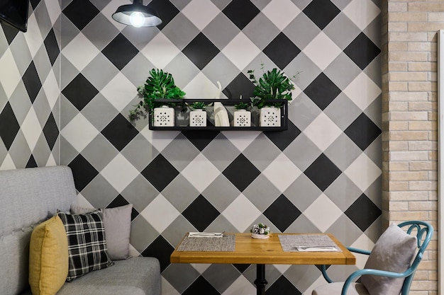 Interior de café vacío con paredes de ajedrez y flores en el estante