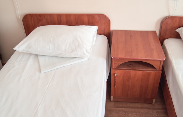 El interior clásico del hotel con camas y mesitas de noche de madera en un dormitorio clásico.