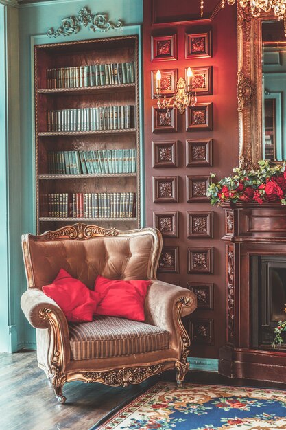 Foto interior clásico de lujo de la biblioteca del hogar. salón con estantería, libros, sillón, sofá y chimenea.