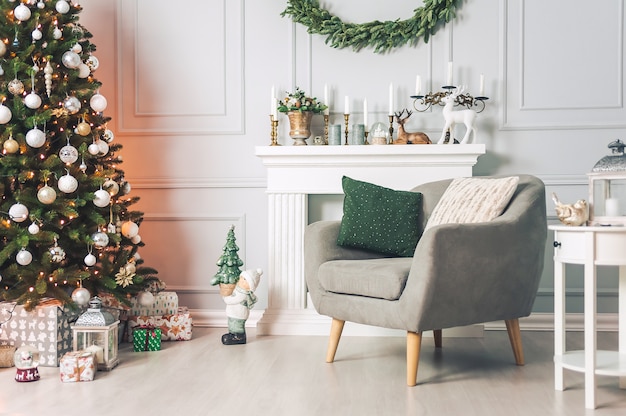 Interior clásico con mesas de sillón y un árbol de Navidad con adornos sobre un fondo claro de una pared con chimenea.