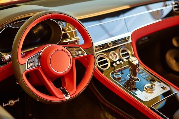 Interior del coche de lujo rojo. Volante, palanca de cambios y salpicadero. Mudada poco profunda.