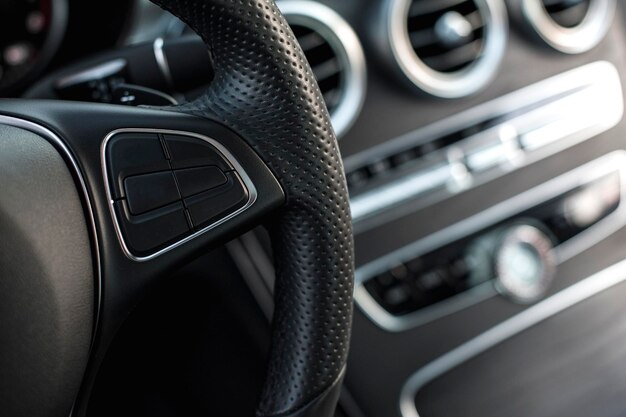 Interior de coche moderno, cuero perforado negro, aluminio, controles de detalles, volante de cuero.