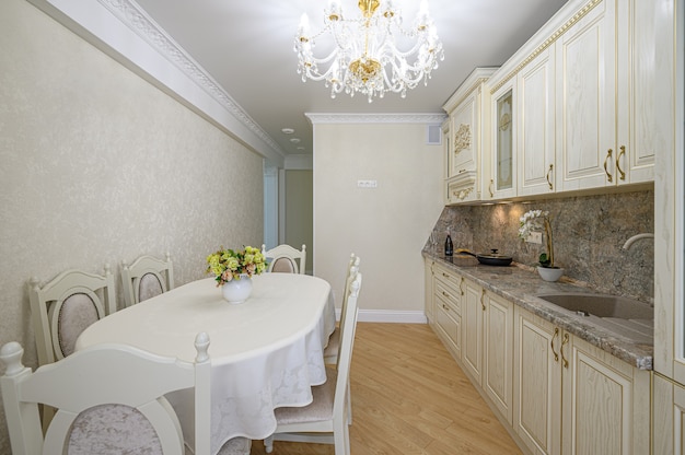 Interior de cocina beige neoclásico moderno de lujo con armario y mesa de comedor