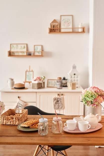 Interior de cocina blanca en estilo loft Estantes con vajilla rosa y utensilios de cocina Apartamento estudio Alquiler y entrega de vivienda Hostal y hotel