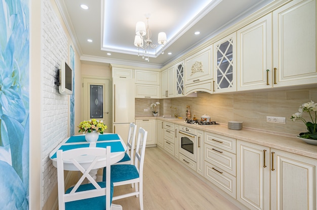 Interior de cocina clásico contemporáneo beige, blanco y cian diseñado en estilo provenzal, todos los muebles con puertas y cajones abiertos