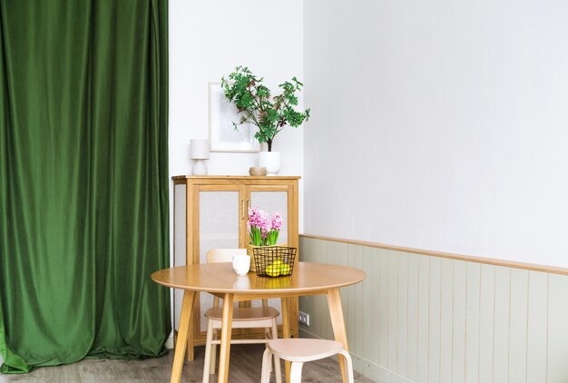 El interior de la cocina está hecho de materiales naturales. Hay plantas, una mesa y una cortina verde en la cocina.