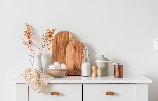 Foto interior de cocina de minimalismo natural de estilo escandinavo aparador de cocina con tazón de huevo, tablas de cortar, jarra y utensilios de cocina