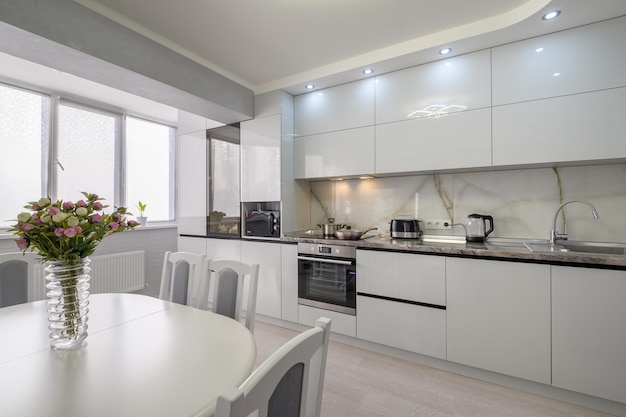 Interior de cocina moderna blanca con mesa de comedor