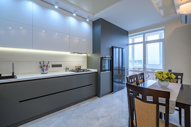 Interior de cocina moderna espaciosa de lujo blanco y gris oscuro con mesa de comedor