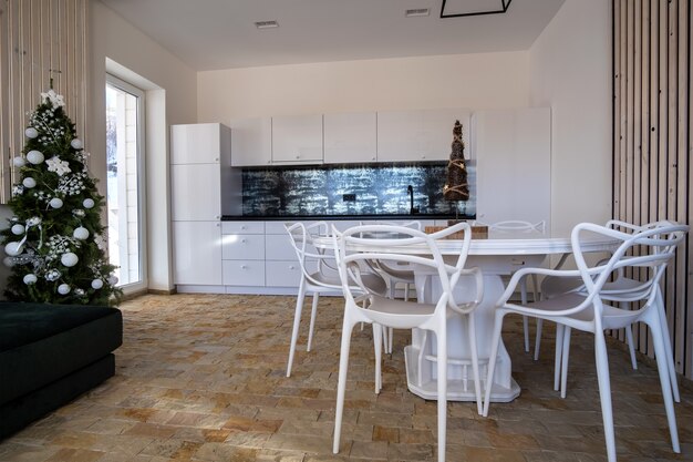 Interior de cocina moderna y espaciosa con paredes blancas, elementos decorativos de madera, muebles contemporáneos y sofá grande y suave.