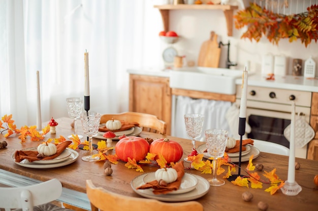 Interior de la cocina de otoño Hojas rojas y amarillas y calabazas en un fondo claro Sirviendo la cena
