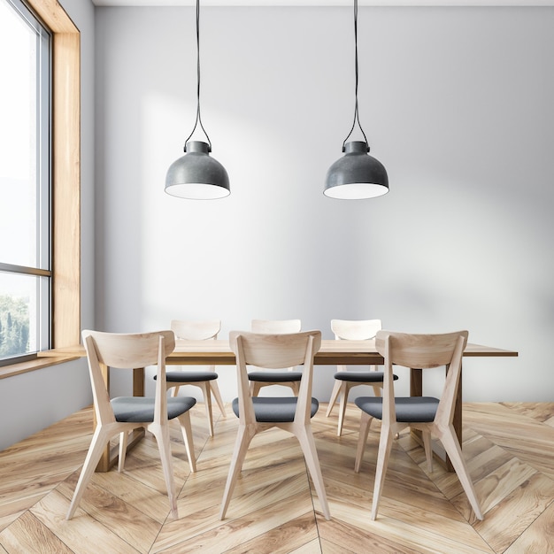 Interior del comedor con paredes grises, piso de madera y mesa de madera con sillas grises y de madera.