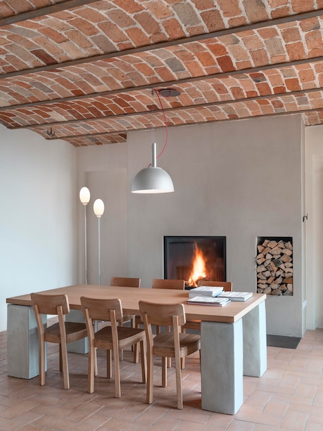 Interior de comedor rústico con suelo de terracota, bóveda de ladrillo y la chimenea moderna