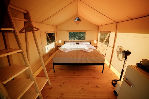 Interior da aconchegante tenda glamping aberta com luz dentro durante o pôr do sol Barraca de acampamento de luxo para férias de verão ao ar livre e conceito de estilo de vida de férias