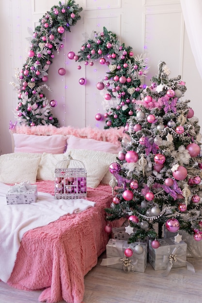 Interior da casa de ano novo em rosa, árvore de natal com balões e uma cama