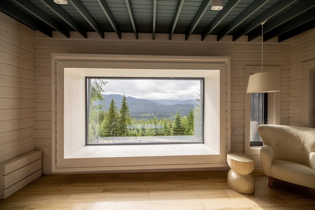 Interior da casa de madeira com janela panorâmica e vista panorâmica sobre as montanhas