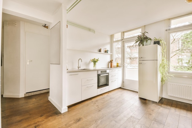 Interior da cozinha leve espaçosa com porta de varanda e janelas em apartamento leve