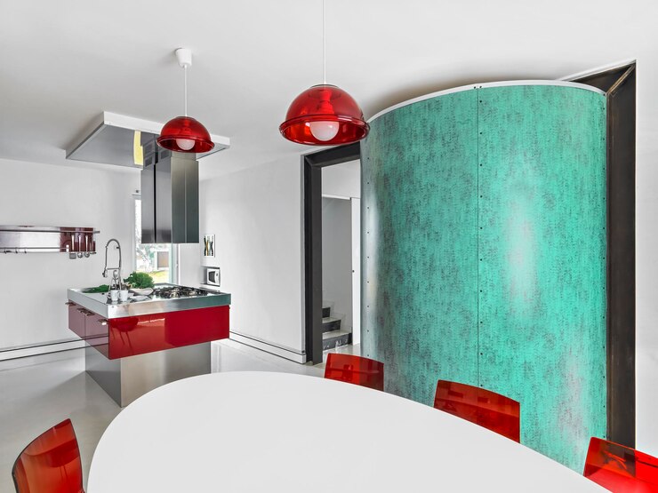 Foto interior da cozinha moderna em primeiro plano a mesa de jantar branca com dois lustres vermelhos no fundo a cozinha da ilha