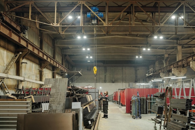 Interior da oficina espaçosa onde o engenheiro ajusta a máquina industrial