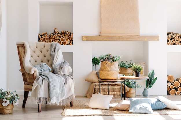 Foto interior da sala de estar bem iluminada em estilo escandinavo com poltrona grande, mesa de escritório e plantas.