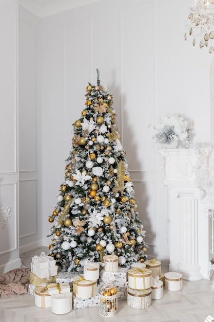 Interior da sala de estar com uma árvore de Natal e decorações Linda árvore de Natal com decoração festiva de ouro branco Conceito de Natal e Ano Novo caixas de presentes e presentes