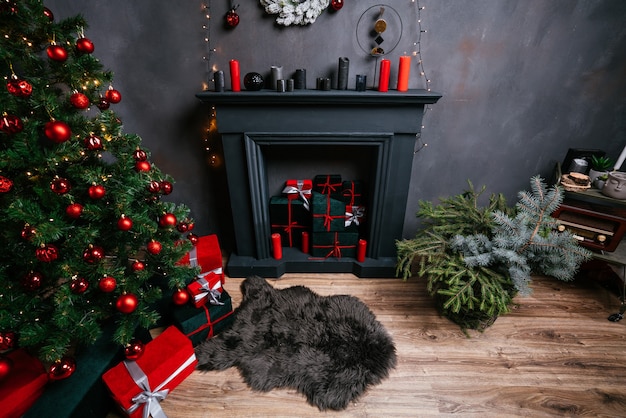 Interior de ano novo 2021 com velas, lâmpadas e bokeh. Quarto decorado para a celebração do natal. Árvore de natal com presentes