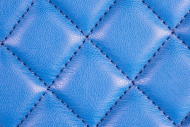 Foto interior de couro azul de carro luxuoso moderno. parte dos detalhes do assento de carro em couro perfurado. fundo azul da textura do couro perfurado. textura, couro artificial com costura diagonal. assentos de couro