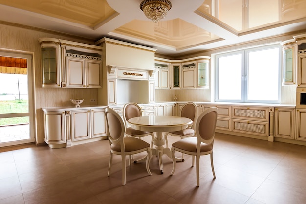 Interior de cozinha moderna e equipada de luxo. Cozinha em casa de luxo com armários bege. Mesa e cadeiras