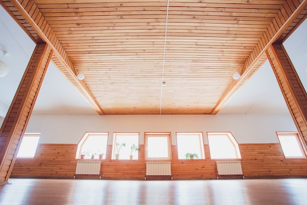 Foto interior de madeira do ginásio com tapete de ioga preto e pequenas janelas