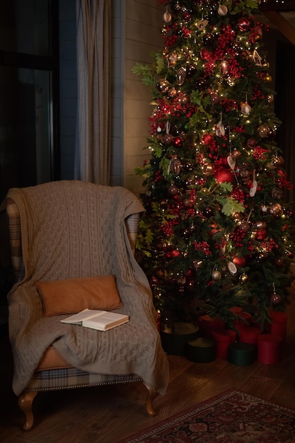 Interior de Natal com poltrona e abeto Uma poltrona fica ao lado de uma árvore de Natal decorada