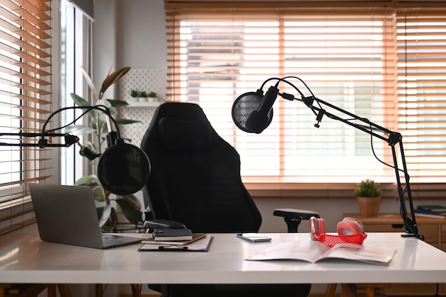 Interior de podcast de estúdio em casa com laptop de microfone profissional e fone de ouvido sem fio tecnologia e conceito de equipamento de áudio