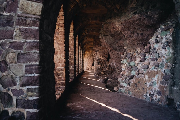 Interior de um antigo túnel de castelo com paredes de pedra e arcos