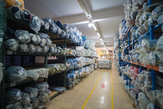 Interior de um armazém industrial com muitas prateleiras com rolos de tecido colorido sobre eles