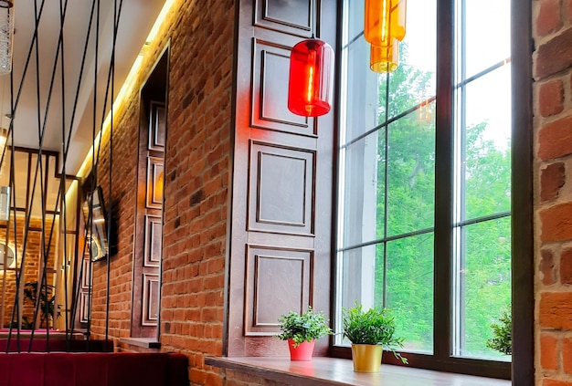 Interior de um café aconchegante com grandes janelas e paredes de tijolos