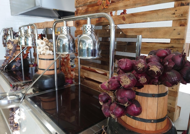 Interior de um restaurante sofisticado com balcões de buffet com bandejas aquecidas para servir e decoração de vegetais frescos secos em barris de madeira