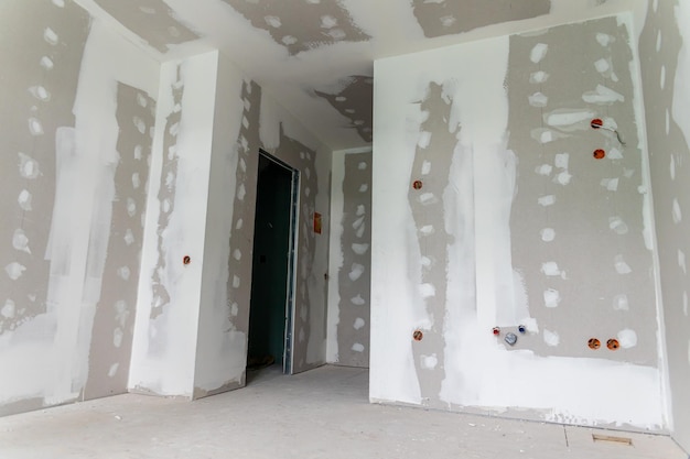 Foto interior de uma casa em renovação com instalação de paredes de gesso e aplicação de compostos conjuntos