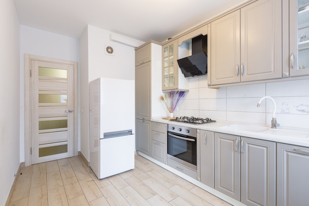 Interior de uma cozinha moderna bege e cinza em um pequeno apartamento elegante