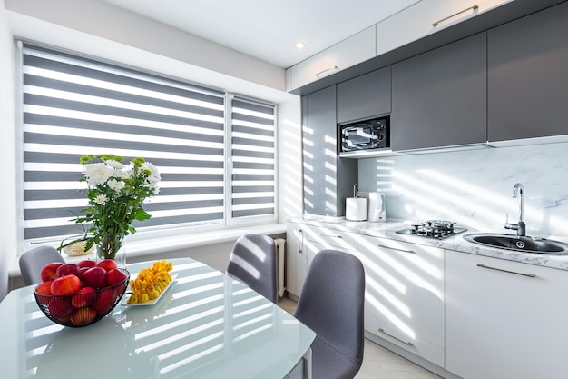 Interior de uma pequena cozinha em branco e cinza, com mesa de jantar